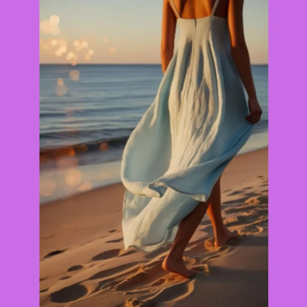 Woman walking barefoot on the beach at sunset in a flowing light blue sundress, capturing relaxed Amazon fashion finds summer coastal vibe and breezy style.