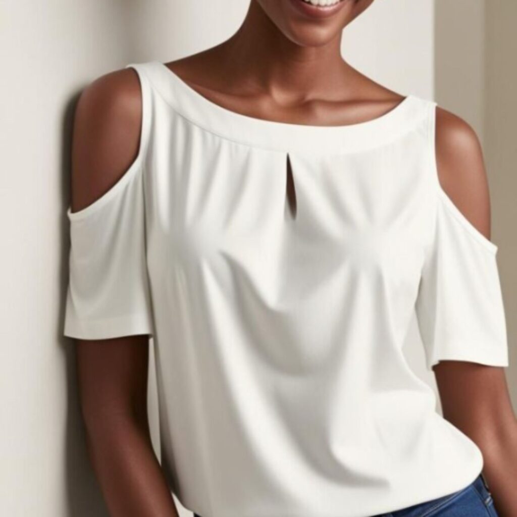 A beautiful woman wearing a white boat-neck blouse with cold shoulders, paired with blue jeans.