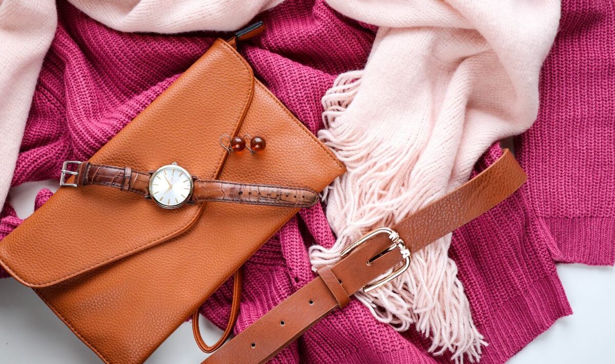 fashion outfit flat lay of pink and blush knit sweaters with tan leather purse, brown belt, earrings, and watch for stylish fall season outfit ideas
